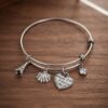 Bracciale acciaio rigido con ciondoli torre conchiglia cuore zircone cubico